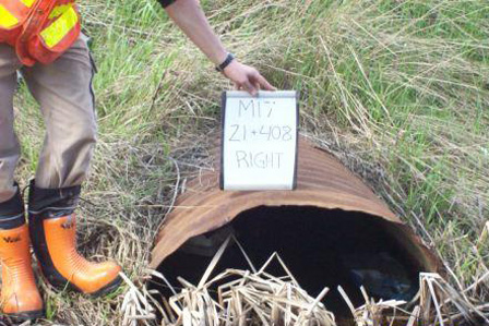 pipe in ditch with person holding sign