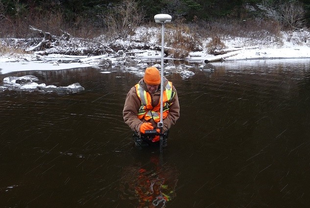 man standing in river with equipment